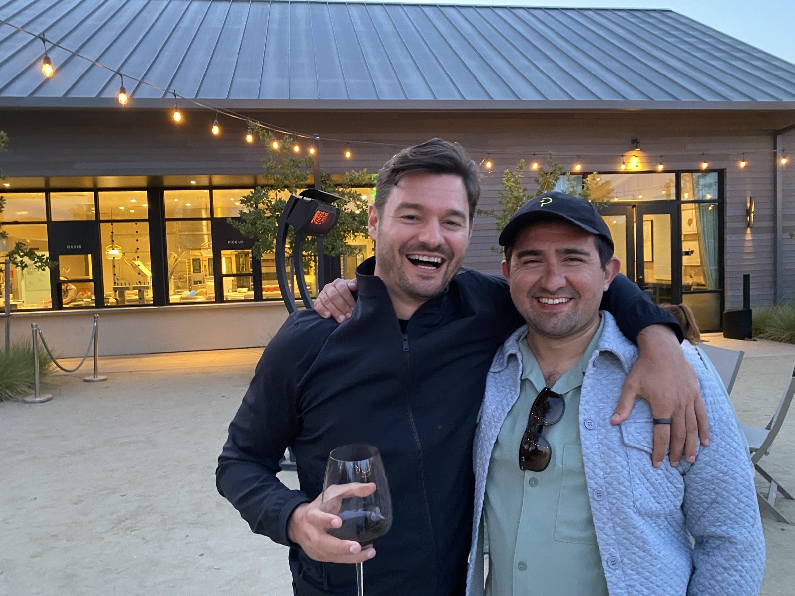 Two founders sharing a glass of wine under string lights at the summit